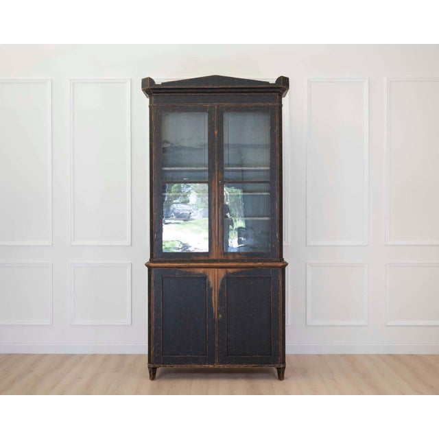 Made in Sweden in the early nineteenth century, around 1820, this tall bookcase has adjustable shelves, a repainted black...