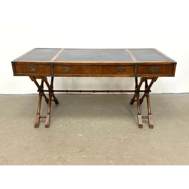 Vintage campaign-style writing desk by Brandt Cabinet Works, featuring a distinctive double trestle base, inset dark top...