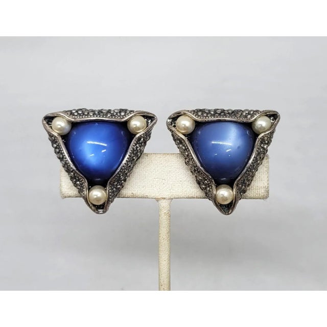 This is part of Chairish’s Costume Jewelry assortment. 1950s triangular silvertone bumpy texture with cabochon blue resin...