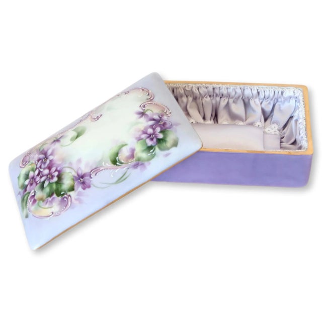 Hand-painted lavender porcelain jewelry or trinket box with satin lining. Maker's mark on underside.
