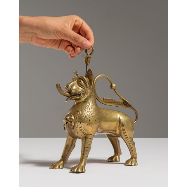 This 19th century brass lion aquamanile oil lamp is cast in brass as a standing lion with a ring handle on its back. The...