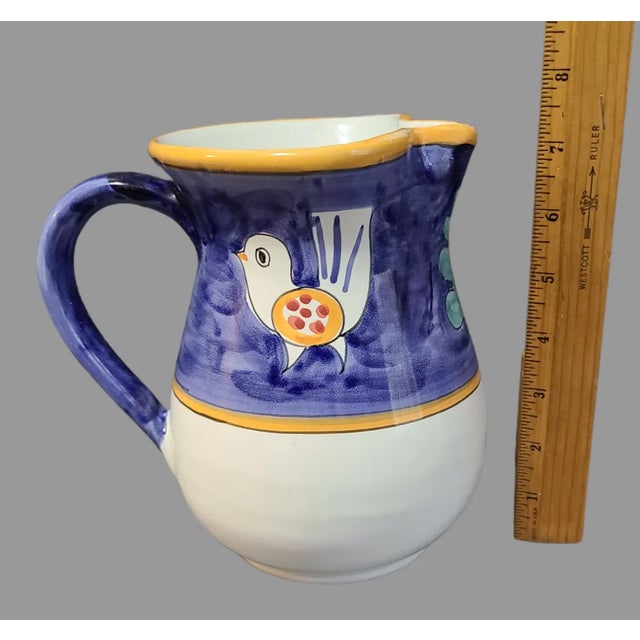 This unique terra-cotta pitcher jug vase showcases beautiful hand-painted with birds and leaf motif features a glossy...