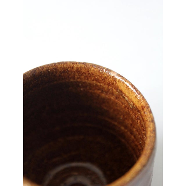 This is a vintage studio pottery cup vase. The handmade wheel-turned ceramic vase features a warm russet brown glaze.