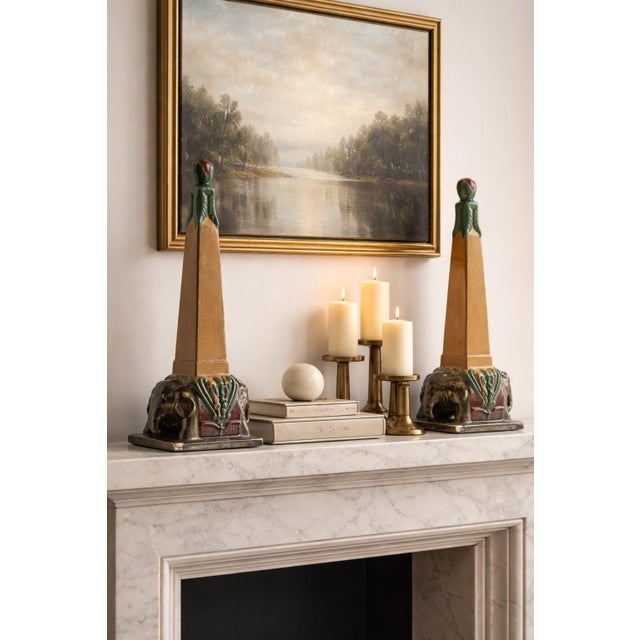 A striking pair of tall Art Deco ceramic sculptures featuring stylized obelisk forms rising from sculptural elephant...