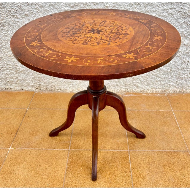 Beautiful 20th-century round side table featuring an ornate marquetry top with floral and geometric inlay work. The...