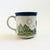 A vintage ceramic mug with the design of a hot air balloon floating over a landscape. Blue interior. Measures 5"W x 3.5"D...
