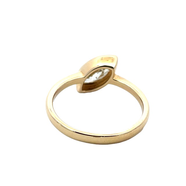 Elegant and modern, this 18K yellow gold ring features a 0.78 carat marquise-cut diamond set horizontally in a sleek bezel...