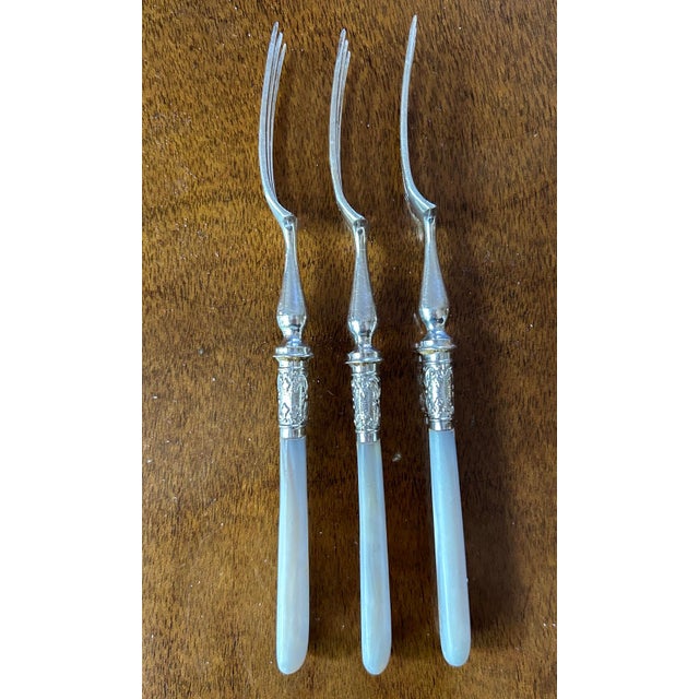 Elegant English serving forks featuring mother of pearl handles and silver plated chafing dish ferrules in classic style....