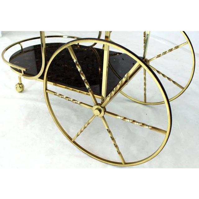 Decorative mid-century modern two-tier bar tea serving cart on large carriage style brass wheels. The lower level is 12" H.