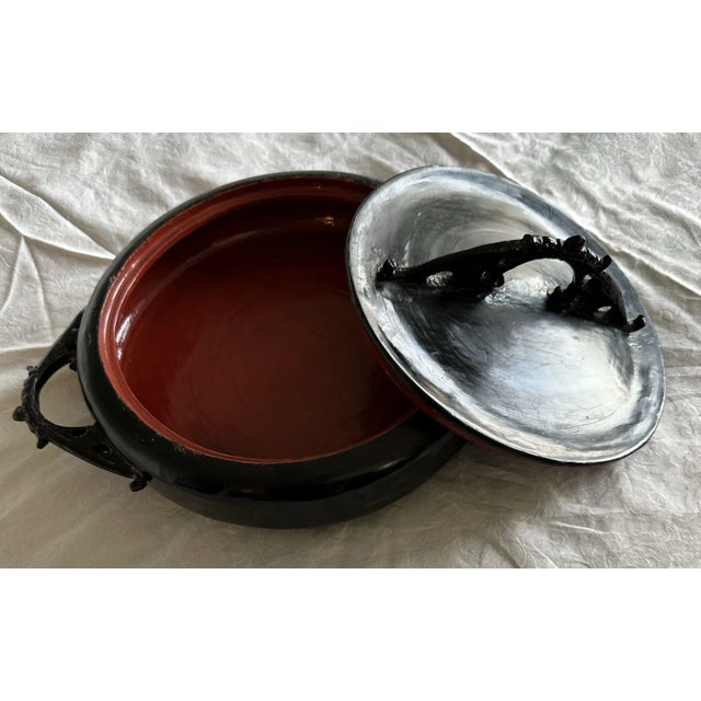 This covered compact “casserole” dish has a flat lid with 2 handles on the side. The inner section is lacquered in red