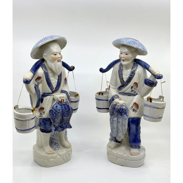 Vintage blue and white chinoiseie man and woman fishing couple. The couple carry two buckets that hang on each side. The...