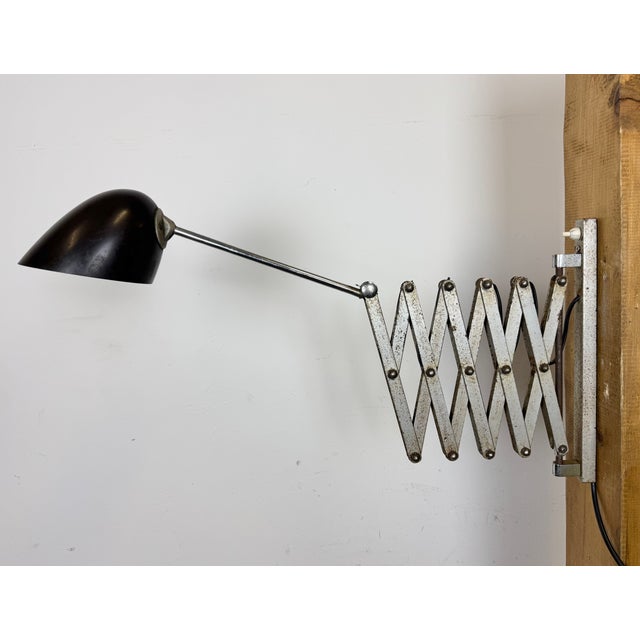 This vintage industrial adjustable scissor wall light was produced in former Czechoslovakia during the 1950s. The lamp has...