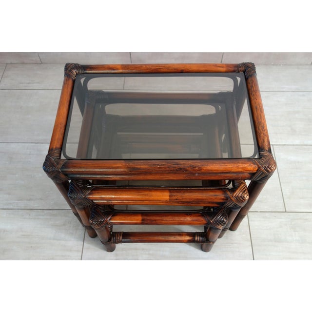 Set of 3 vintage nesting tables from the 1960s, France. Bamboo legs, wicker binding, lightly smoked glass top. The set is...