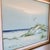 A signed vintage oil painting depicting a serene coastal landscape with white sand dunes, sea oats, rolling waves, and a...