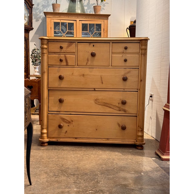 A handsome English pine chest of drawers in a warm honey tone, the rounded top above a bank of five small drawers over...