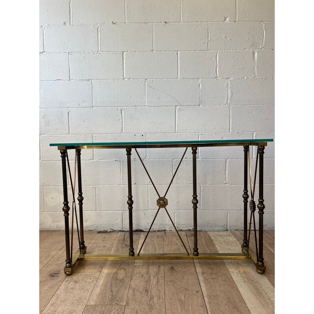 A refined Hollywood Regency console table dating to the 1970s, featuring a polished brass frame with elegant turned...