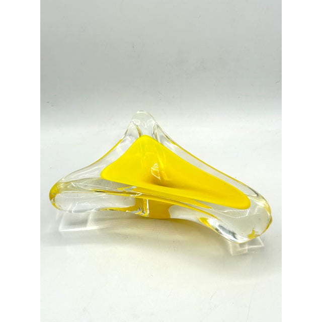 A sculptural mid-century Murano glass catchall bowl featuring vibrant yellow glass encased in clear glass using the...