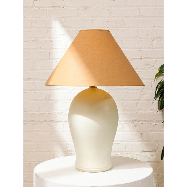A beautifully understated vintage table lamp featuring a substantial white sculptural base with a softly rounded,...
