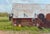 While They Work by Stephanie Hartshorn | Oil on Wood Panel Rustic barn with farm equipment and greenery For Sale