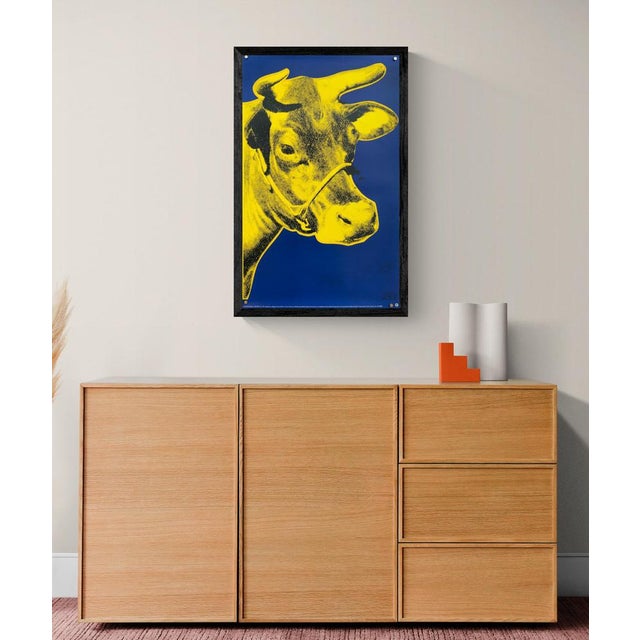 The Piece This vibrant vintage poster features Andy Warhol's celebrated "Cow" motif, presenting a bright yellow bovine...