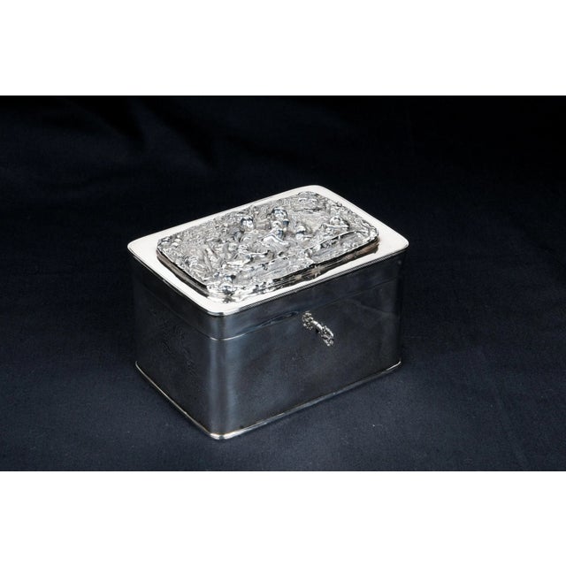 Continental Silverplate Box. Late 19th Century High relief putti & stylized foliage in central reserve. Lock with key....
