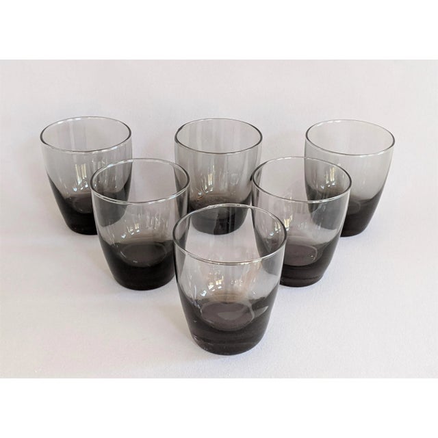 A set of eight mid-century smoke gray lowball glasses. The vintage Libbey glassware feature a weighted bottom with fluted...