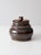 This is a vintage handmade studio pottery jar with a fitted lid. It features a richly variegated brown glaze and a hand-...