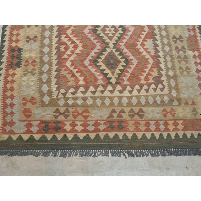 vintage handwoven kilim features a bold tribal design with four stacked diamond medallions framed by rhythmic geometric...