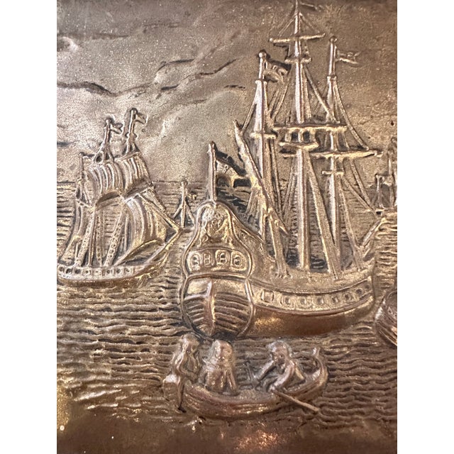 A rectangular brass-clad box with a hinged lid, decorated on both the lid and front panel with raised repoussé scenes of...