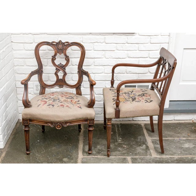 A coordinating pair of intricately carved vintage Regency style armchairs with finely crafted needlepoint seat cushions...