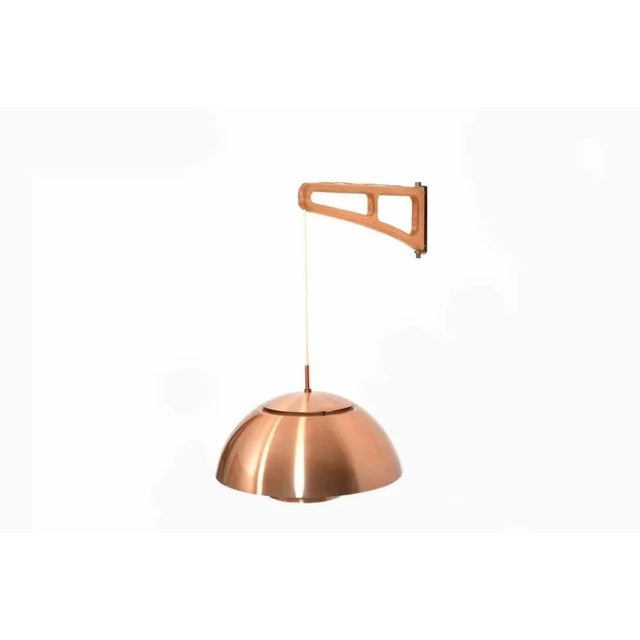 Infinitely swiveling wall lamp with a copper shade, a oak and brass swivel arm suspension. Denmark 1960s. Size: Arm: 47 cm...