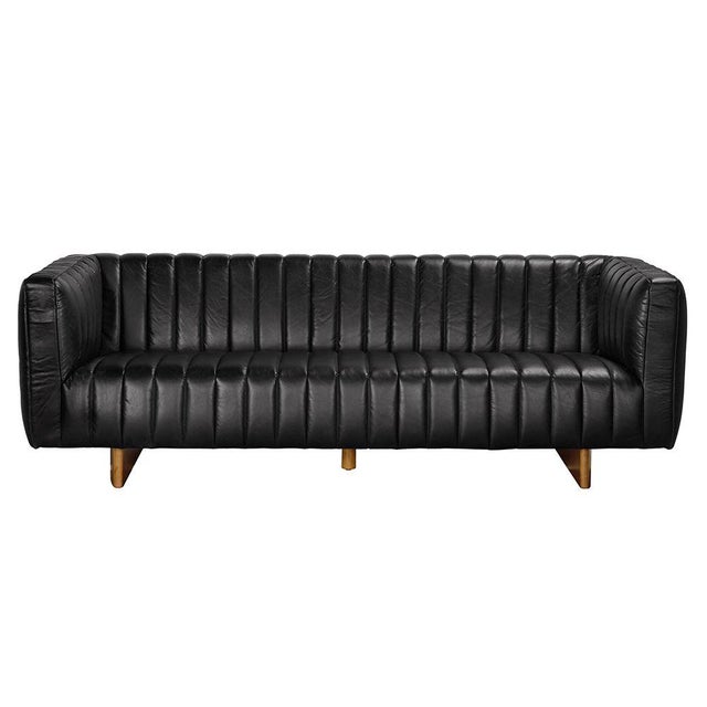 This modern tuxedo sofa in black leather features a dark walnut sled-leg that subtly elevates the channeled upholstery....