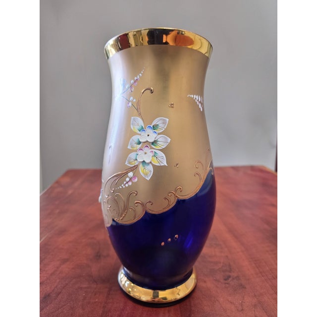 A vintage Bohemian Egermann vase crafted from cobalt blue glass with 24k gold detailing and applied enamel flowers.