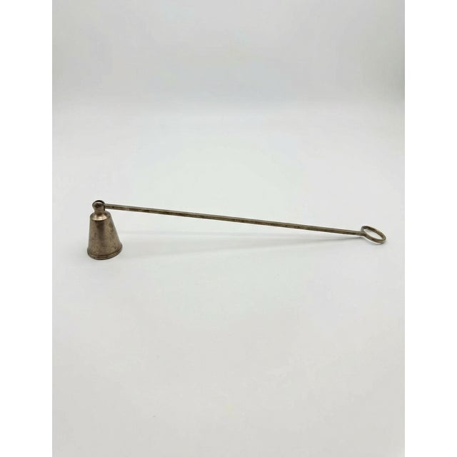 Elegant antique candle snuffer featuring a long handle and classic bell-shaped tip. Likely silver or silver-plated, with a...