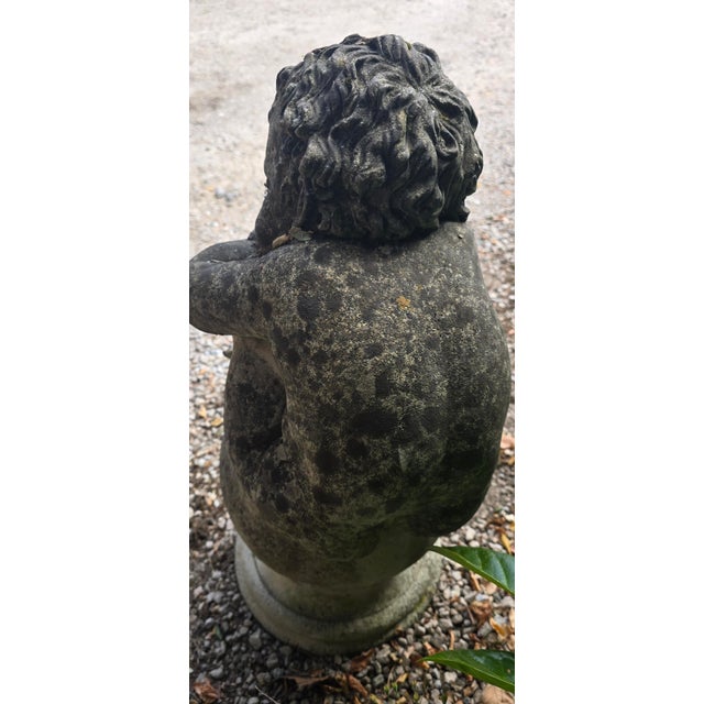 A very rare, well weathered stone sleeping cherub on socle base, with carved writing o the back (illegible), in overall...