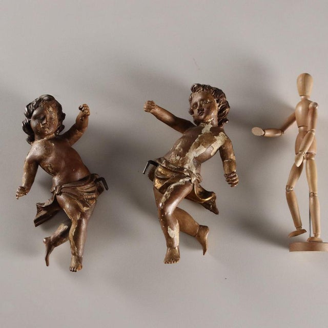 A pair of carved, lacquered, and gilded wooden cherubs. The sculptures were part of a larger composition. This piece is...