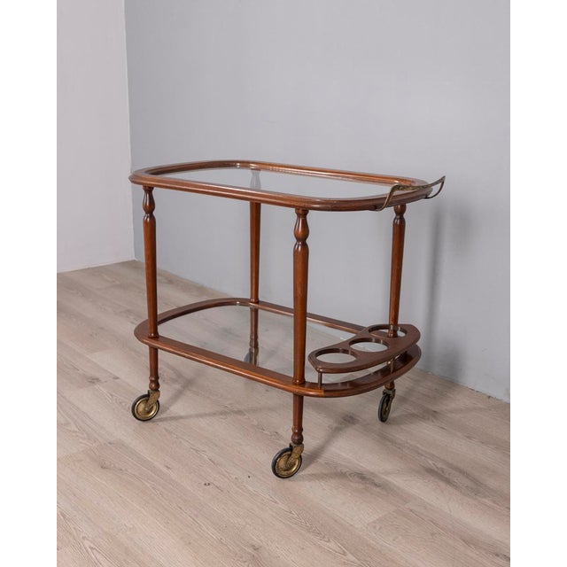 Bar trolley with wooden structure and clear glass shelves, bottle holder on the lower level and gilded brass handle,...