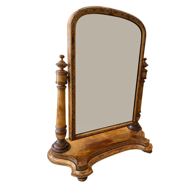 Arched mirror frame with painted decoration flanked by columns with turned finials, shaped platform base. Flat bun feet.