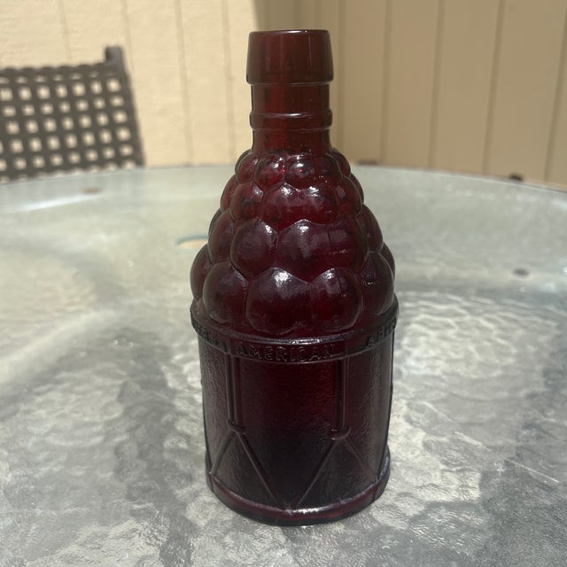 This is a vintage 1970s ruby red glass "McGiver's American Army Bitters" bottle produced by Wheaton Glass in Millville,...