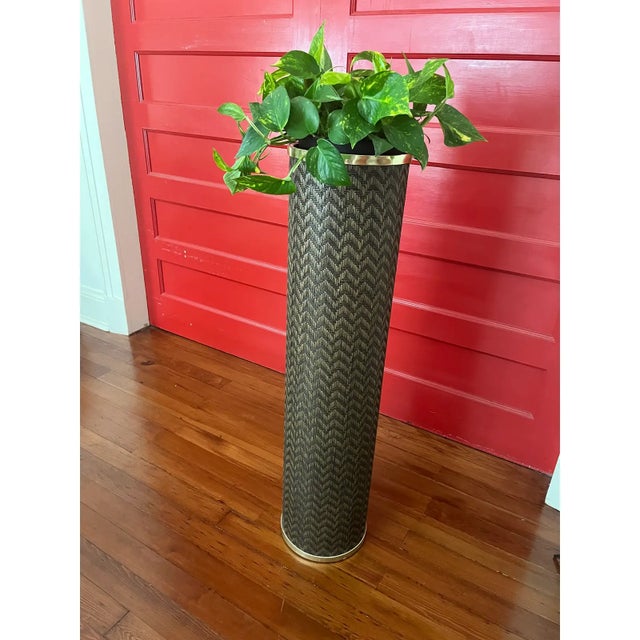 This vintage 1960s floor planter features a tall cylindrical woven form in a rich dark finish, accented with a brass rim....