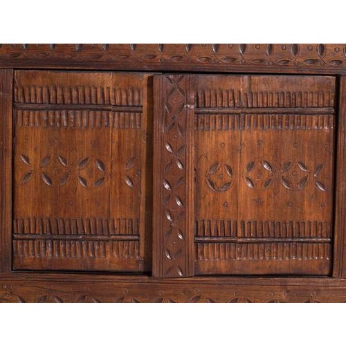 This antique carved sideboard in pine wood is a Uyghur cabinet from Xinjiang with four carved doors and a lobed-arch...