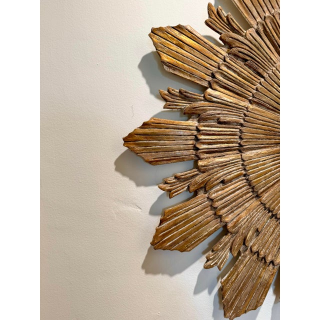 Unusual, Beautifully wood carved and giltwood mid century vintage sunburst mirror, with hidden clock face. Hands are...