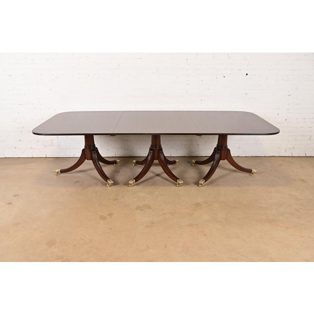 A gorgeous English Georgian or Regency style triple pedestal extension dining table In the manner of Baker Furniture...