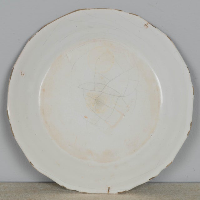 A late 18th century French faience plate with hand-painted decoration entitled Les Sans Culottes 1790. This is a faience...