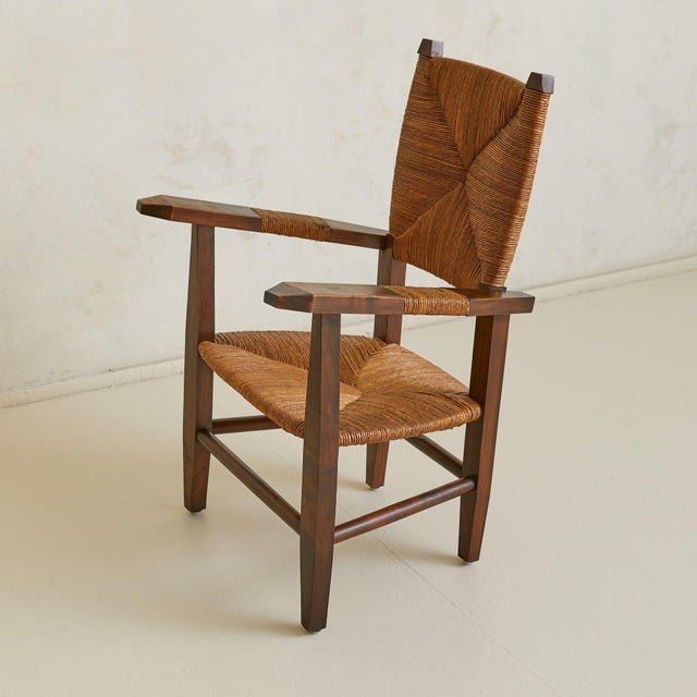 A French armchair from the 1940s, crafted in solid wood with a handwoven natural rush seat and backrest. The frame rises...