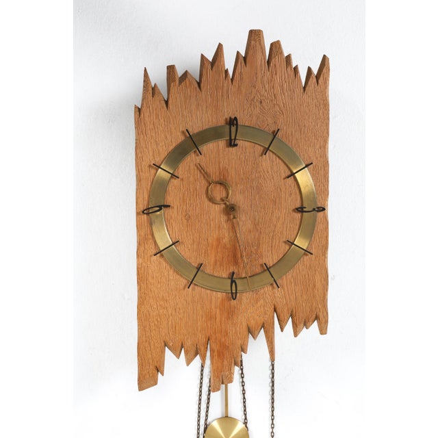 wall clock with oak body and brass dial and works. germany, circa 1960s. sculptural oak silhouette with brass accents....