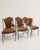 A set of six mid-century dining chairs attributed to Frederic Weinberg, combining slender black-lacquered wrought iron...