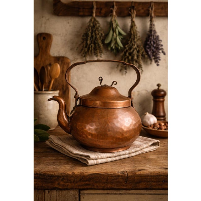 This antique hand-hammered copper kettle showcases a beautifully rounded, globular form with a warm, naturally aged...