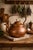 This antique hand-hammered copper kettle showcases a beautifully rounded, globular form with a warm, naturally aged...