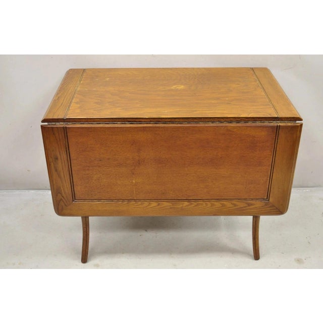 Vintage Mid Century Modern Klismos Saber Leg Oak Wood Drop Leaf Dining Table. Center table top appears to be oak plywood,...